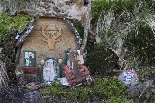 Ein aus Naturmaterialien gebasteltes Modellhaus auf dem bemoosten Waldboden
