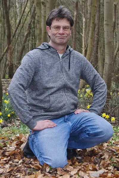 Ein Mann hockt am Waldboden im Frühling